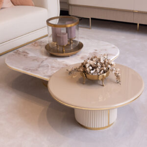 Modern coffee table set with a cream high-gloss finish, marble-effect top, fluted detailing, and sleek gold legs, styled in an elegant living room setting.