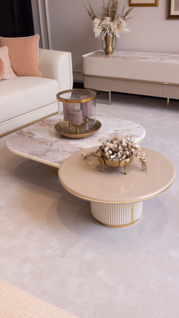 Modern coffee table set with a cream high-gloss finish, marble-effect top, fluted detailing, and sleek gold legs, styled in an elegant living room setting.