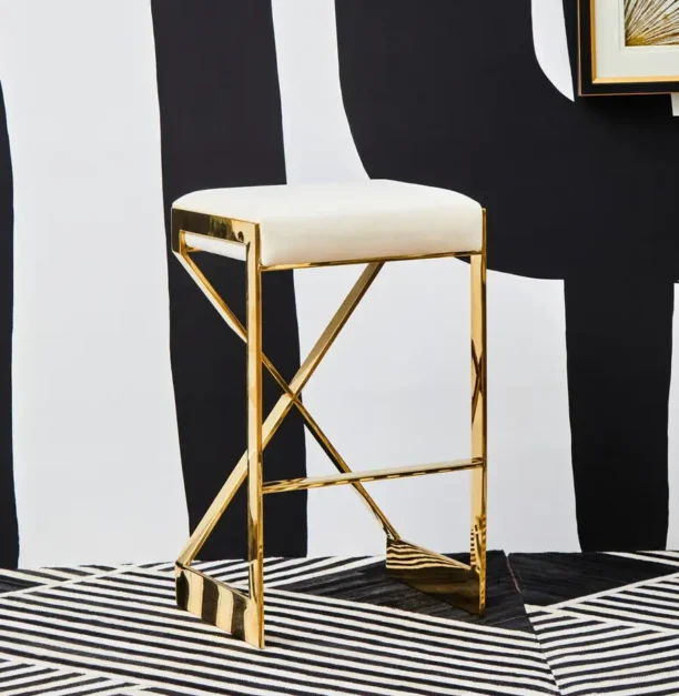 Celine Bar Stool with ivory velvet seat, featuring a gold or chrome X-shaped stainless steel frame and footrest for added support.