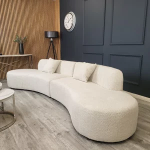 An elegant Bellino 5-seater curved sofa upholstered in luxurious cream bouclé fabric, featuring a smooth, continuous curved design that enhances comfort and adds a modern, sophisticated touch to any living space.