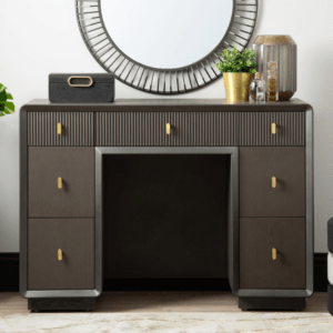 The Amelie Smoke Grey Elm 7 Drawer Dressing Table is a chic furniture piece made of MDF with a sleek veneer finish in an alluring grey tone. This elegant table boasts seven drawers, offering ample storage while exuding modern sophistication, perfect for enhancing any dressing or bedroom space with both style and functionality