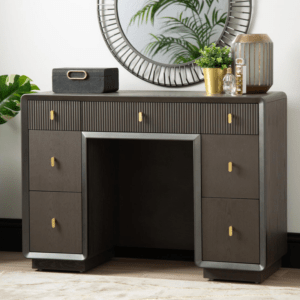 The Amelie Smoke Grey Elm 7 Drawer Dressing Table is a chic furniture piece made of MDF with a sleek veneer finish in an alluring grey tone. This elegant table boasts seven drawers, offering ample storage while exuding modern sophistication, perfect for enhancing any dressing or bedroom space with both style and functionality