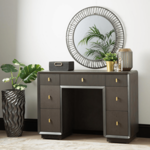 The Amelie Smoke Grey Elm 7 Drawer Dressing Table is a chic furniture piece made of MDF with a sleek veneer finish in an alluring grey tone. This elegant table boasts seven drawers, offering ample storage while exuding modern sophistication, perfect for enhancing any dressing or bedroom space with both style and functionality