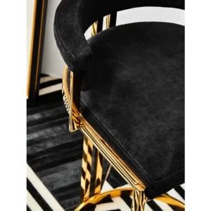 Elevate your bar area with the Piermont Bar Stool, boasting a luxurious black and gold color scheme. Inspired by the opulence of art deco design, its curved backrest and u-shaped base exude glamour. Wrapped in sumptuous velvet, the seat and backrest offer both style and comfort. Add a touch of sophistication to your space with the Piermont Bar Stool today