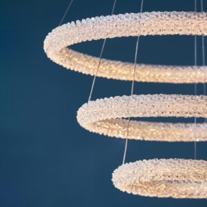 Presenting our distinctive chrome-plated ceiling light, featuring three interconnected hoops adorned with clear crystals, reminiscent of rapidly formed ice crystals. This exquisite chandelier boasts over 9,000 faceted crystals meticulously arranged to captivate the eye. Suspended gracefully by delicate and adjustable clear wire cables, it can be positioned above dining tables, in bedrooms, or as a stunning centerpiece in living rooms, adding a remarkable touch to your interior decor.