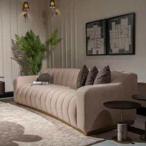 A cream-colored modern sofa featuring a sleek design with a luxurious gold plinth base, providing a sophisticated and elegant look suitable for contemporary interior settings.