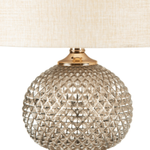 A sleek clear glass table lamp with a stacked ring-style base topped by a cream linen shade.