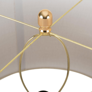 A sleek clear glass table lamp with a stacked ring-style base topped by a cream linen shade.