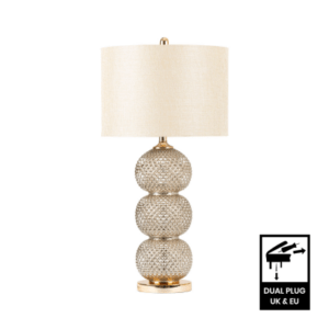 A sleek clear glass table lamp with a stacked ring-style base topped by a cream linen shade.