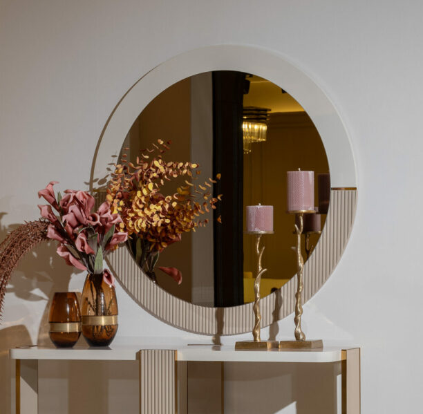 Belize Mirror with a round shape, featuring a modern design with split beige and cream colors, detailed rivet edging, and intricate gold detailing.