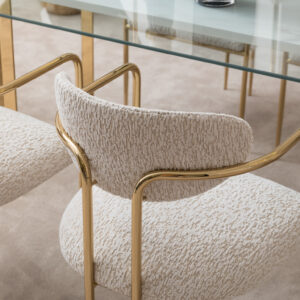 Elegant dining room featuring the Santorini Luxury Dining Set with a marble centerpiece and sleek glass top, surrounded by bespoke dining chairs upholstered in luxurious boucle fabric with gold metal frames, set against a stylish, modern interior