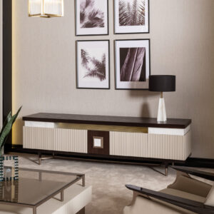 A spacious living room with a luxury TV unit featuring a dark wood top, cream and gold accents, and ribbed detailing, complemented by a matching coffee table and armchair.