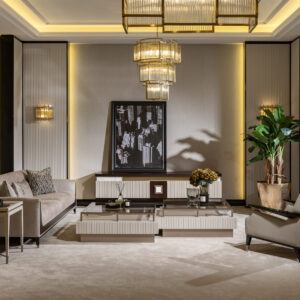 A spacious living room with a luxury TV unit featuring a dark wood top, cream and gold accents, and ribbed detailing, complemented by a matching coffee table and armchair.