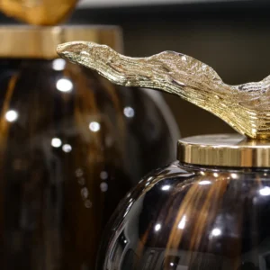 Make a bold statement with the Arlo Grande Decorative Jar, a stunning piece that beautifully blends rich chocolate and ebony tones. Its luxurious glazed finish is perfectly complemented by an elegant gold lid, creating a sophisticated focal point for any console or shelf.