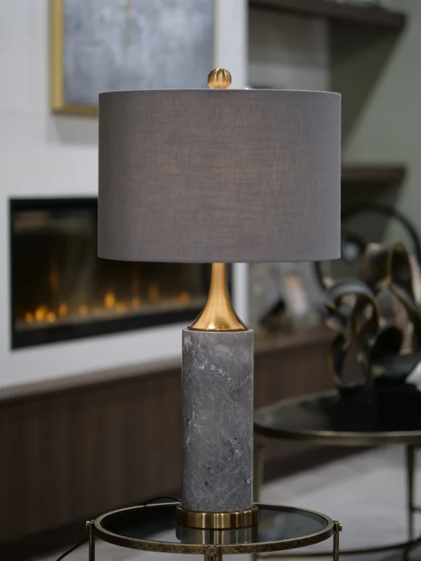 The Valencia Marble Table Lamp blends luxurious materials with timeless design. Featuring a striking grey marble base, this lamp exudes natural elegance and sophistication. The gleaming gold brass accents enhance its refined look, while the rich slate grey shade offers a perfect balance of modern and classic style. Whether placed in a contemporary or traditional setting, the Valencia Lamp adds a touch of opulence to any room. Due to the natural marble used, each lamp is uniquely beautiful with slight variations in color and finish. Features: Elegant Grey Marble Base: Naturally unique and luxurious. Gold Brass Accents: Adds a touch of opulence and refinement. Slate Grey Shade: Completes the design with subtle elegance. Timeless Design: Perfect for both modern and classic interiors.