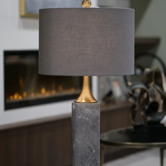 The Valencia Marble Table Lamp blends luxurious materials with timeless design. Featuring a striking grey marble base, this lamp exudes natural elegance and sophistication. The gleaming gold brass accents enhance its refined look, while the rich slate grey shade offers a perfect balance of modern and classic style. Whether placed in a contemporary or traditional setting, the Valencia Lamp adds a touch of opulence to any room. Due to the natural marble used, each lamp is uniquely beautiful with slight variations in color and finish. Features: Elegant Grey Marble Base: Naturally unique and luxurious. Gold Brass Accents: Adds a touch of opulence and refinement. Slate Grey Shade: Completes the design with subtle elegance. Timeless Design: Perfect for both modern and classic interiors.