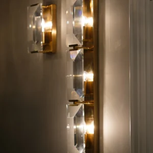 Belgravia crystal and brass wall light with faceted glass prisms reflecting light, luxury lighting for modern and classic interiors.