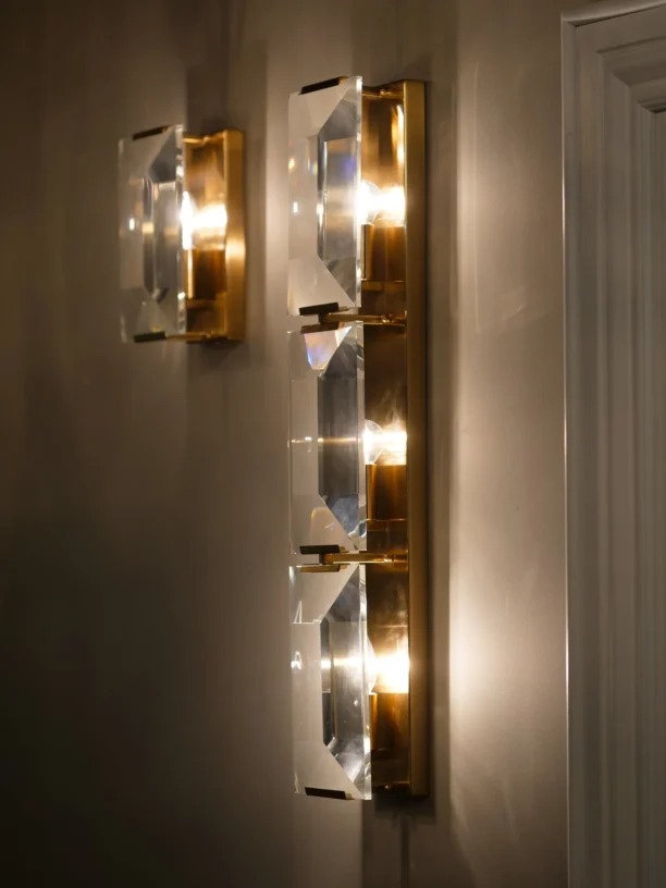 The Belgravia Wall Light exudes boldness and glamour, making it a standout piece for any room. Crafted with faceted crystal prisms and brass, it beautifully reflects and refracts light, reminiscent of emerald-cut diamonds. This luxurious crystal and brass wall light is the perfect addition to any space, combining timeless elegance with modern sophistication.