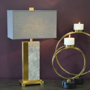 The Solara Marble & Brass Table Lamp is a contemporary piece featuring a sleek white marble stem with brass accents and base. Standing at 77cm, this elegant lamp adds a refined touch to any room in your home. Each lamp is unique due to the natural stone variations, making it a perfect statement piece. Pair with the matching floor lamp for a cohesive look. Features and Benefits: Height: 77cm, Shade Diameter: 43cm White marble stem with brass accents and base Unique natural stone variations in each piece Matching floor lamp available for a complete look