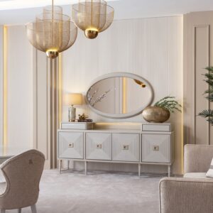 Sophisticated dining room featuring the cream Lusso dining set with a bronze-accented oval table, plush chairs, and a matching sideboard, complemented by golden decor and modern pendant lighting, in a neutral-toned interior.