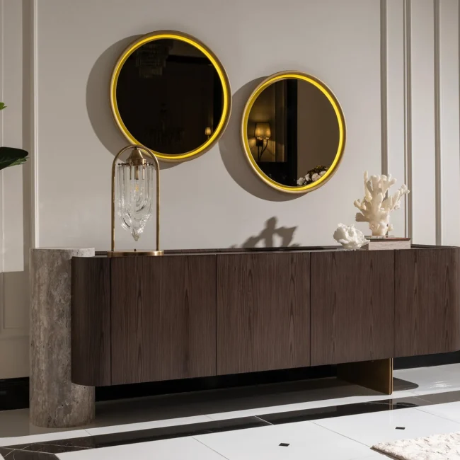 Palermo sideboard with dark wood veneer, travertine stone pillar, and brushed gold base; paired with a round led mirror.