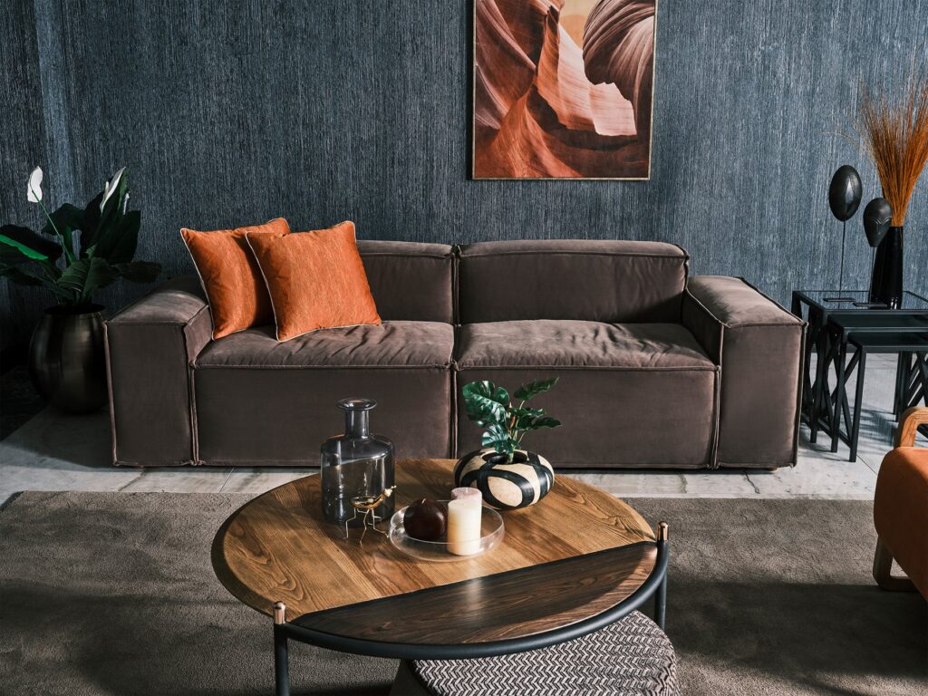 Elegant Sierra Sofa in a light fabric finish, accented with rust-colored scatter cushions, displayed in a contemporary living room.